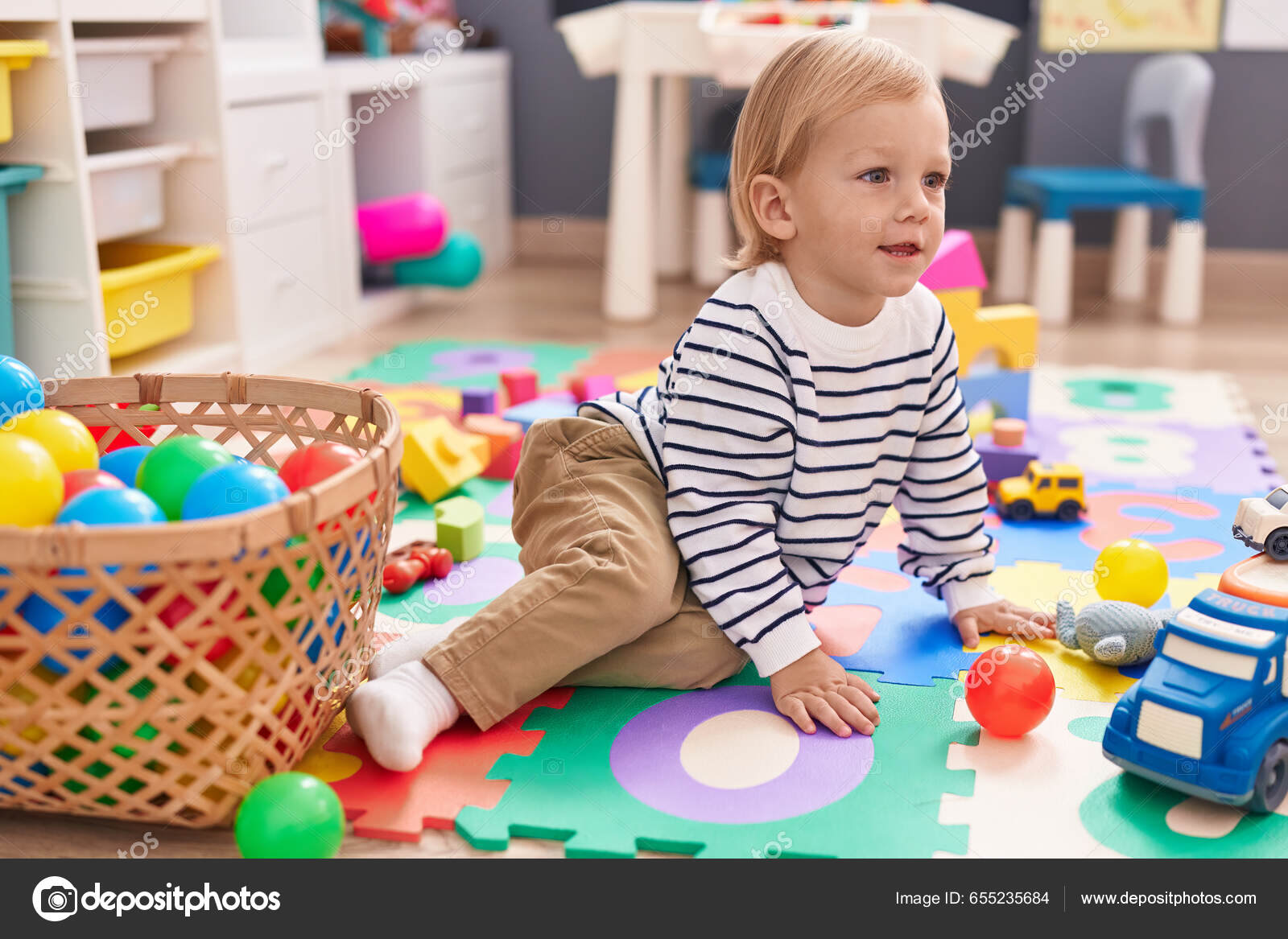 Adorável bebê caucasiano brincando com bolas sentadas no chão no jardim de  infância