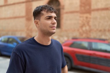 Latin kökenli genç adam ciddi bir ifadeyle sokağa bakıyor.