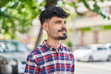 Young hispanic man smiling confident looking to the side at street