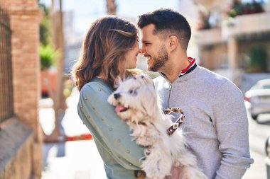 Man and woman holding dog standing together at street