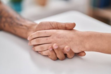 Man and woman couple sitting on table with hands together at home