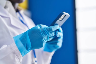 Genç Afrikalı Amerikalı kadın bilim adamı laboratuvarda akıllı telefon kullanıyor.