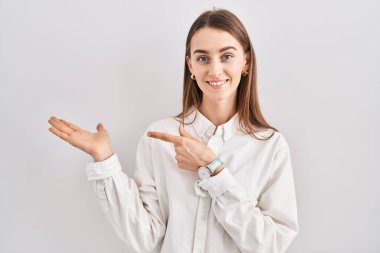 İzole edilmiş arka planda duran genç beyaz kadın kameraya hayret ediyor ve gülümsüyor.. 