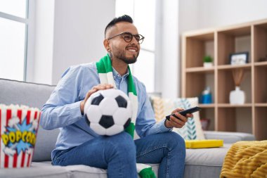 Genç İspanyol futbolcu holigan elinde top tutan destek takımı kameraya seksi bir ifadeyle bakıyor, neşeli ve mutlu bir yüzle. 