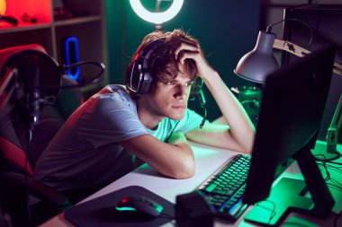 Young blond man streamer stressed using computer at gaming room