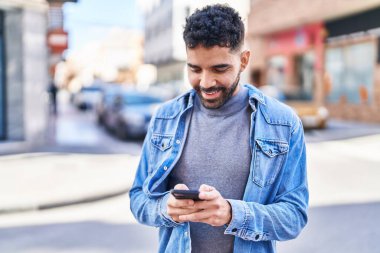 Sokakta akıllı telefon kullanan, kendine güvenen genç bir İspanyol.