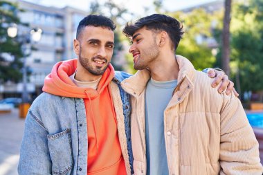 İki erkek parkta birbirlerine sarılıyorlar.