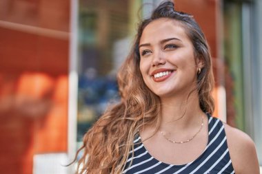Young beautiful hispanic woman smiling confident looking to the side at street