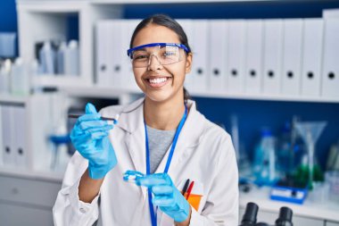 Genç Afrikalı Amerikalı kadın bilim adamı laboratuarda haplar tutuyor.