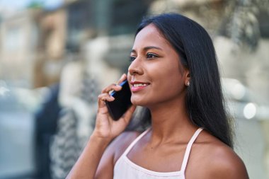 Genç, güzel bir kadın, gülümsüyor. Kendine güveniyor. Akıllı telefondan konuşuyor.