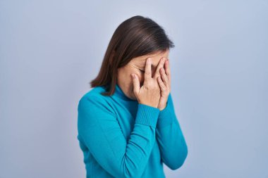 Middle age hispanic woman standing over isolated background with sad expression covering face with hands while crying. depression concept. 