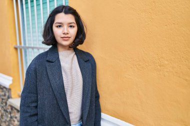 Sokakta rahat bir ifadeyle kameraya bakan genç bir kadın.