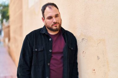 Young hispanic man with relaxed expression standing at street