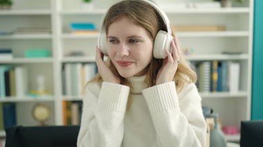 Young blonde woman student smiling confident listening to music at library university