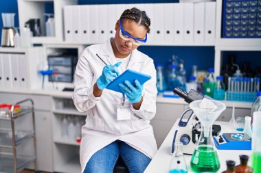 African american woman scientist using touchpad at laboratory