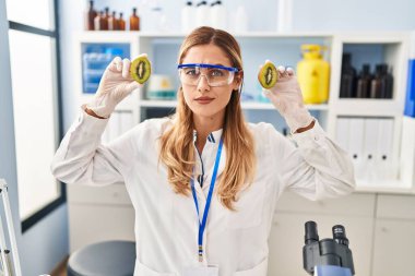 Young blonde scientist woman working with food at laboratory skeptic and nervous, frowning upset because of problem. negative person. 