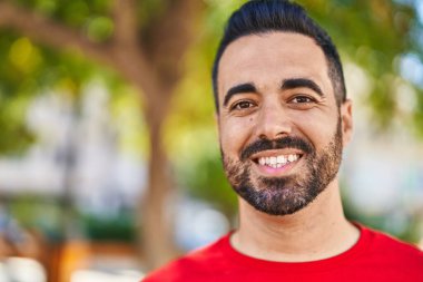 Parkta kendinden emin gülümseyen İspanyol genç adam.