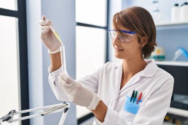 Genç ve güzel İspanyol bilim kadını laboratuarda test tüpüne sıvı döküyor.