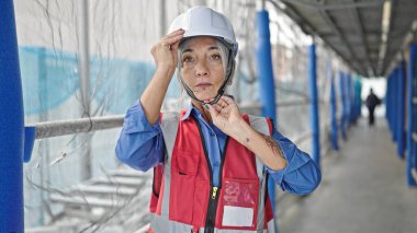 Orta yaşlı, gri saçlı, kadın müteahhit sokakta rahat bir ifadeyle duruyor.