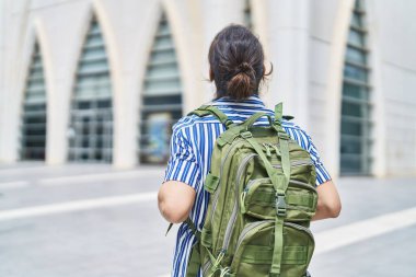 Young hispanic man tourist wearing backpack walking at street