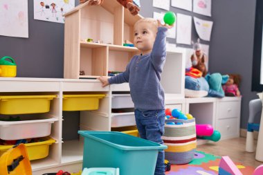 Sevimli beyaz çocuk anaokulunda taşaklarıyla oynuyor.