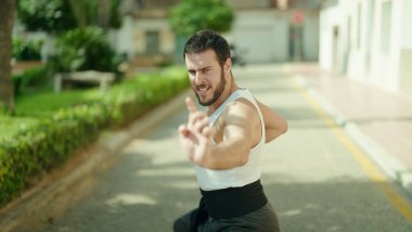 Genç İspanyol adam parkta karate dövüşçüsü eğitimi alıyor.