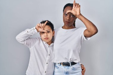 Genç anne ve oğul beyaz arka planda yan yana durur. Alnında parmakları olan insanlarla alay eder. Ezik hareketler yapar, alay eder, hakaret ederler.. 