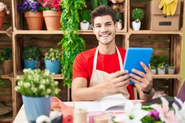 Çiçekçide dokunmatik ped kullanarak gülümseyen İspanyol çiçekçi.