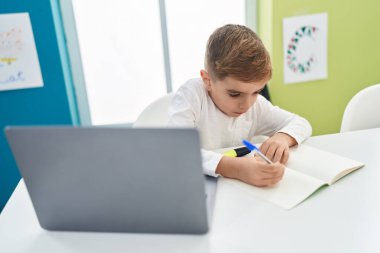 Sınıfta dizüstü bilgisayar kullanarak notlar yazan sevimli İspanyol öğrenci.