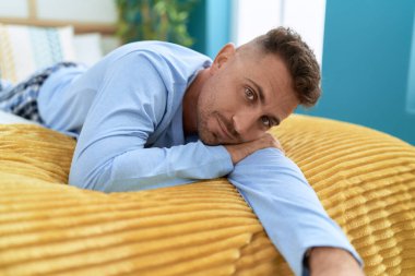 Genç İspanyol adam yatak odasında rahat bir ifadeyle yatakta yatıyor.