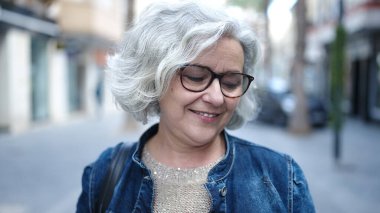 Middle age woman with grey hair smiling confident at street
