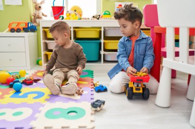 Arabalarla oynayan sevimli çocuklar. Anaokulunda yerde oturan oyuncak ve traktör.