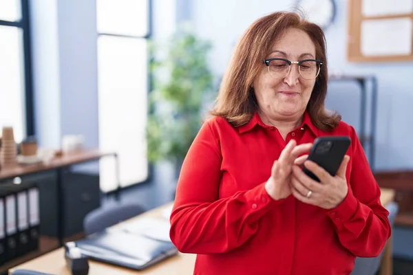 オフィスでスマートフォンを使うシニア女性ビジネスワーカー — ストック写真