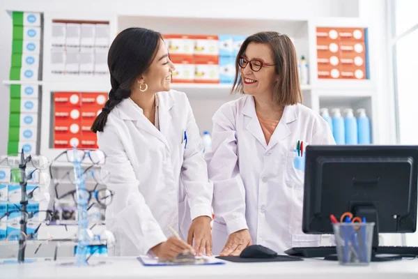 Two Women Pharmacist Smiling Confident Writing Document Pharmacy — стоковое фото