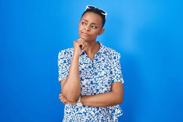 Mujer Afroamericana Pie Sobre Fondo Azul Con Mano Barbilla Pensando —  Fotos de Stock