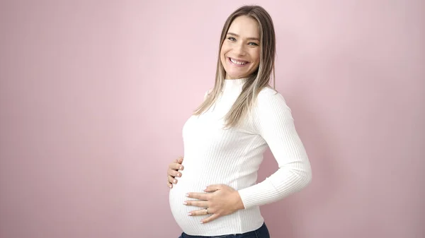 Mladá Těhotná Žena Usmívá Sebevědomě Dotýká Břicho Přes Izolované Růžové — Stock fotografie