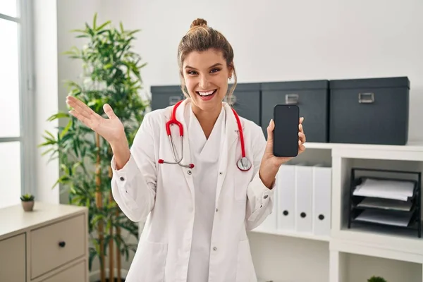 Jonge Vrouw Doktersuniform Houdt Smartphone Vieren Prestatie Met Vrolijke Glimlach — Stockfoto