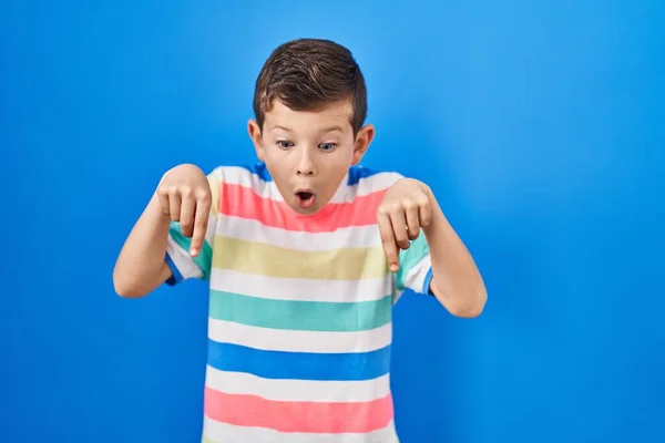 Młody Biały Dzieciak Stojący Nad Niebieskim Tłem Palcami Pokazującymi Reklamę — Zdjęcie stockowe