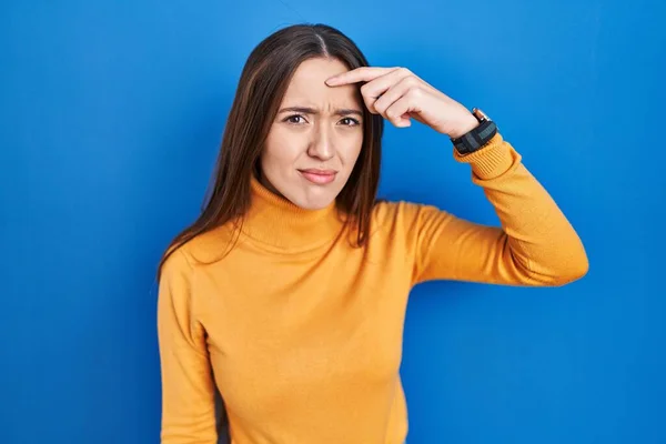 Young Brunette Woman Standing Blue Background Pointing Unhappy Pimple Forehead — Stock Photo, Image