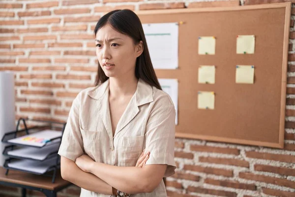 Chinese young woman working at the office doing presentation skeptic and nervous, disapproving expression on face with crossed arms. negative person.