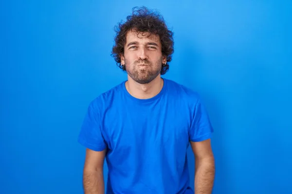 Hispanic Young Man Standing Blue Background Puffing Cheeks Funny Face — Φωτογραφία Αρχείου