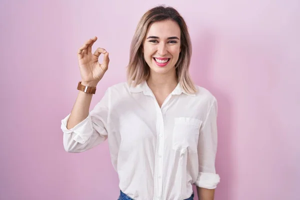 ピンクの背景の上に立つ若い美しい女性は 手と指でOkサインを行う積極的な笑顔 成功した表現 — ストック写真