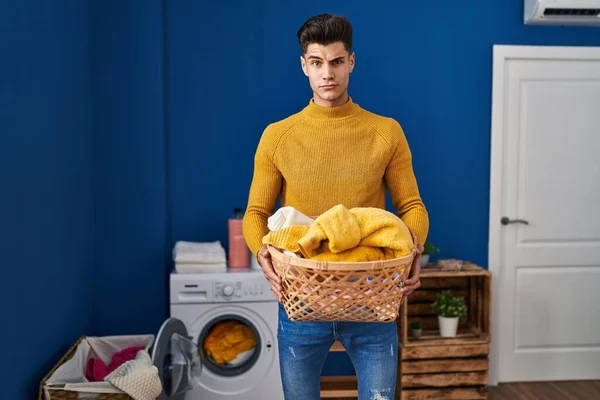 Young hispanic man holding laundry basket skeptic and nervous, frowning upset because of problem. negative person.