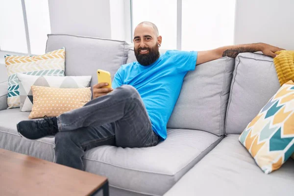 Mladý Plešatý Muž Pomocí Smartphone Sedí Pohovce Doma — Stock fotografie