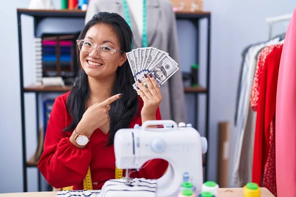 Ασιάτισσα Νεαρή Σχεδιάστρια Ενδυμάτων Κρατώντας Δολάρια Χαμογελώντας Χαρούμενη Δείχνοντας Χέρι — Φωτογραφία Αρχείου