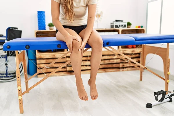 Young Beautiful Hispanic Woman Patient Suffering Knee Pain Sitting Massage — стоковое фото