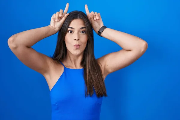 Mavi Arka Planda Dikilen Spanyol Kadın Boynuz Gibi Parmaklarıyla Komik — Stok fotoğraf