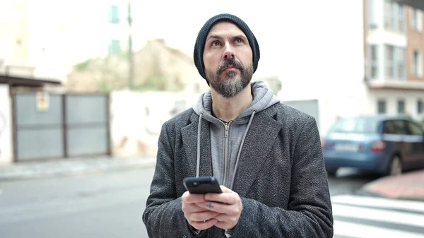 Stock image Young bald man using smartphone with serious expression at street