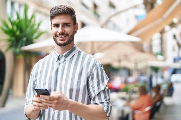 Junger Kaukasier Lächelt Selbstbewusst Mit Smartphone Auf Café Terrasse — Stockfoto