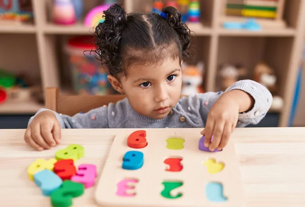 stock image Adorable hispanic girl playing with maths puzzle game sitting on table at kindergarten